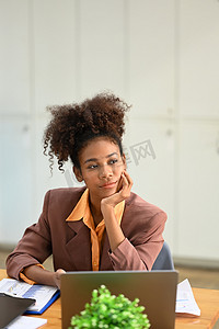 坐着的会计摄影照片_体贴的非洲裔美国女商人坐在工作场所，望着窗外思考项目的成功