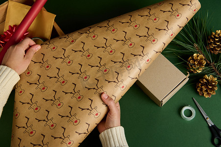 顶视图女人的手推出带有鹿图案的装饰性包装礼品纸包装礼物圣诞准备