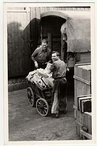 复古照片显示男人将小箱子上传到货车（卡车）。