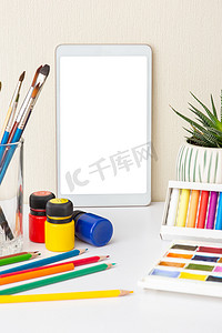带数字平板电脑和彩色绘图用品的桌子