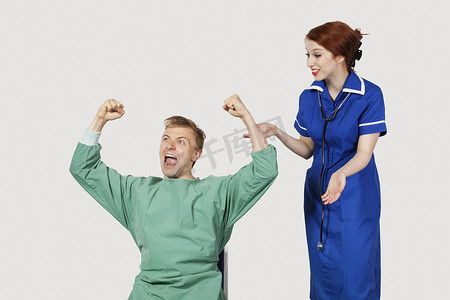 年轻男性患者和女护士在灰色背景下庆祝成功
