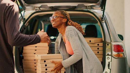从汽车后备箱运送披萨盒的女快递员