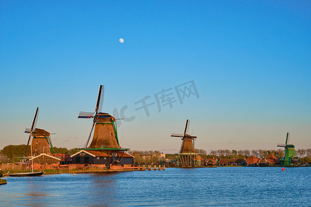 河夕阳摄影照片_荷兰桑斯安斯风车村的风车在日落的暮色中。