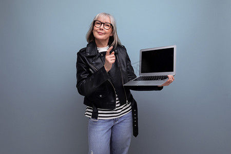 做模型摄影照片_头发花白的成熟老妇人在明亮背景下使用笔记本电脑技术和模型做得很好