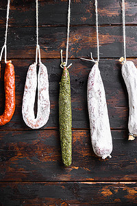 架子肉摄影照片_西班牙干香肠挂在市场上木质表面的架子上