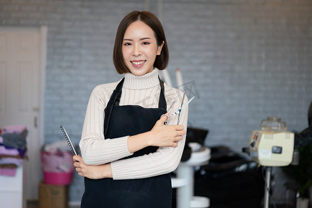 手持合格理发工具的年轻亚洲女美发师的画像。