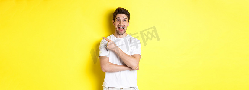 兴奋的微笑男子展示黑色星期五优惠的图片，手指向右，看起来很惊讶，站在黄色背景上