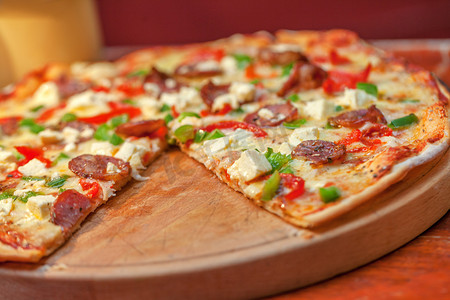餐厅餐桌上的食物、奶酪和比萨饼，配有马苏里拉奶酪、意大利腊肠和香草。