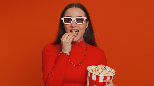 电影视频片摄影照片_戴着 3D 眼镜的兴奋女人吃爆米花，看有趣的电视连续剧、体育游戏电影