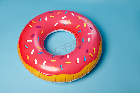 粉红色充气游泳圈甜甜圈，救生圈，隔离在蓝色背景上。