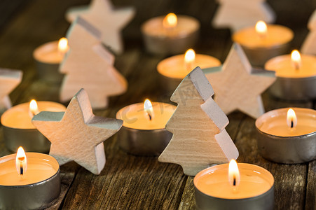 星形和火焰摄影照片_节日燃烧的圣诞蜡烛，配有白色木制圣诞树和星形装饰