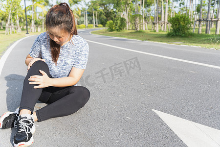 受伤女孩摄影照片_亚洲女性在 r 上跑步时用手抓住膝盖受伤