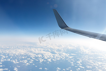 一架飞机的机翼在蓝云之上的天空中。