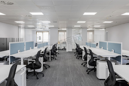 办公区域摄影照片_宽敞空旷的灰色办公室，配有舒适的办公家具，没有带私人区域的设备，让员工工作舒适。