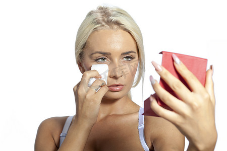 年轻女人用湿巾擦脸，手里拿着镜子
