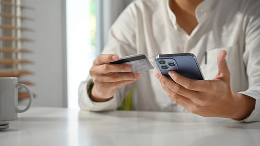 手持信用卡和手机通过互联网下订单或在手机银行应用程序上进行交易