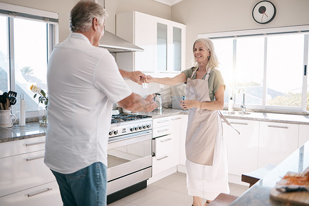 老年夫妇，在厨房、房子或家庭住宅中结合和跳舞，以支持信任、爱或有趣的能量庆祝活动。