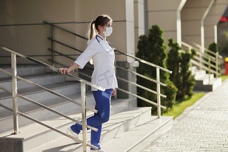 戴防护面罩的女医生或护士走上楼梯