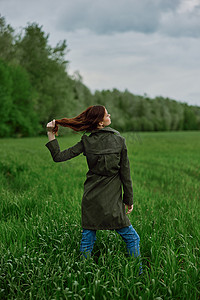 春天雨天，一位身穿深色外套的美女站在绿地里，拉直头发