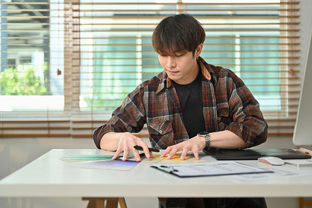 年轻的亚洲男性平面设计师在创意家庭工作室制作色样样本图以创建新系列
