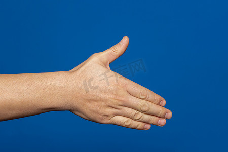 伸出手摄影照片_男人伸出手来与蓝色背景上孤立的握手。