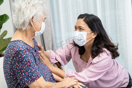 护理人员帮助并与戴着面罩的亚洲老年或老年老妇人交谈，以保护公园内的安全感染 Covid19 Coronavirus。