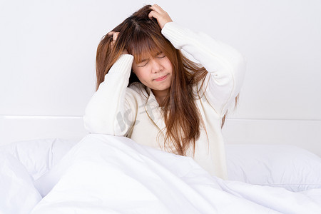 疼痛摄影照片_在床上醒来后患有头痛的年轻女子。