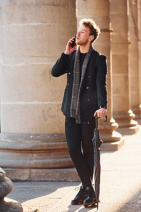 优雅的年轻人穿着正式优雅的衣服站在城市户外打电话