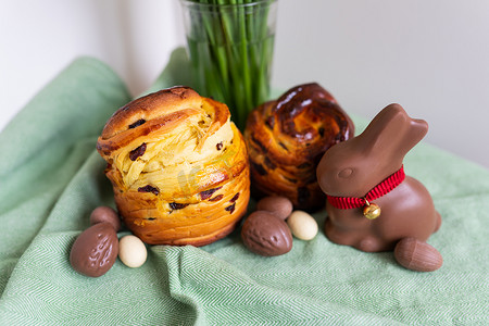 自制的复活节传统糕点放在绿色餐巾纸上，上面放着一束鲜花、一只兔子和巧克力蛋。
