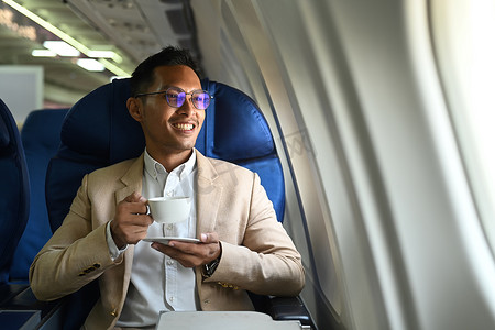商务旅行期间，穿着优雅豪华西装喝咖啡，透过飞机窗户看的成功商人