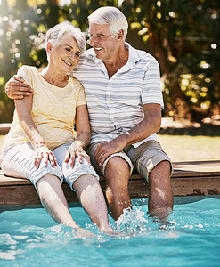 水拥抱摄影照片_老年夫妇在游泳池边拥抱和微笑，在暑假里一起放松、相爱或度过美好的亲密时光。