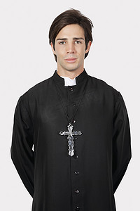 灰色背景下穿着牧师服装的年轻人肖像
