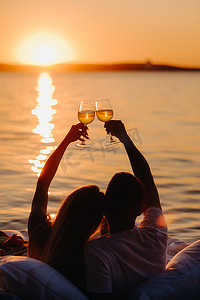 夏日傍晚，日落时分，一对幸福的情侣在海边举起眼镜的轮廓
