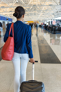 女旅客穿过机场航站楼前往登机口，携带钱包和随身携带的手提行李进行飞行旅行