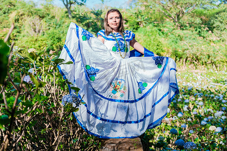 在米尔弗洛雷斯的田野里穿着传统民族服装的尼加拉瓜妇女，在鲜花环绕的田野里身着民族民族服装的微笑女人。