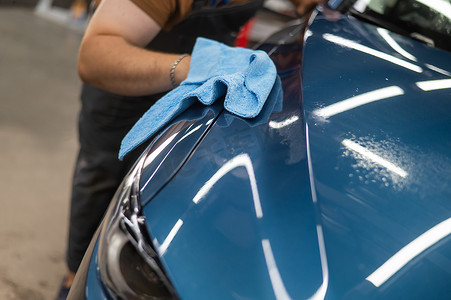 汽车服务师傅在贴上防护装甲膜后，用餐巾纸擦拭汽车。