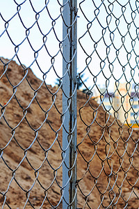 金属栅栏后建筑工地的沙堆