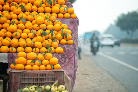 柑橘类水果摄影照片_橘子 kinnu 柑橘类水果堆积在路边摊上，展示了农民如何在夏季传统上将这种当地水果作为健康食品在印度出售以供食用和榨汁