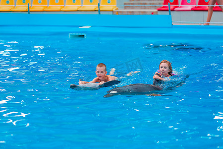 快乐的小孩在海豚馆与海豚一起游泳