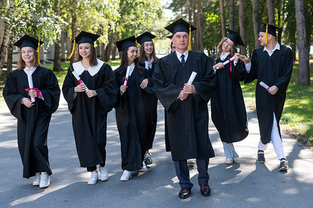 一群穿着长袍、手里拿着毕业证的毕业生走出门外。