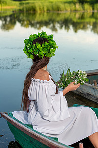 这条河摄影照片_这位仙女留着长长的黑发，穿着一件白色的复古连衣裙，坐在河中央的一条船上。