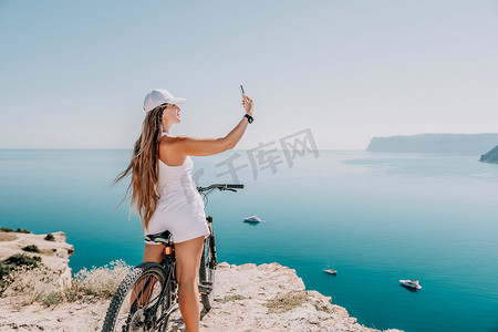 一位骑山地自行车的女自行车手，眺望山海风光。