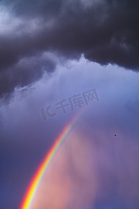 阳光冲破风雨如磐的天空，形成一道奇妙的彩虹