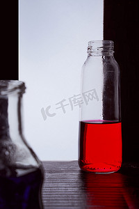 菜单黑金摄影照片_瓶装在浅色背景上，带有蓝色和红色液体剪影照片