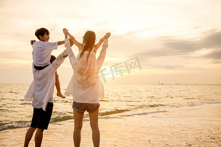 父亲背着儿子，母亲背着女儿肩扛夏日海滩