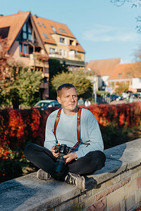 坐在老欧洲城市和拿着照相机的人。