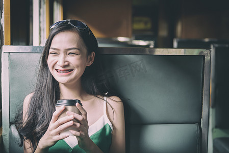 兰芳园丝袜奶茶摄影照片_亚洲女旅客在火车上喝咖啡，开心
