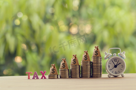 金融税概念：文字税、闹钟、美国钱袋上一排排上升的硬币。