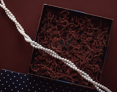 节日礼物、珍珠首饰项链和豪华礼物的美容盒订阅包模型，巧克力背景上空空的开放礼盒平铺作为在线购物交付，平铺