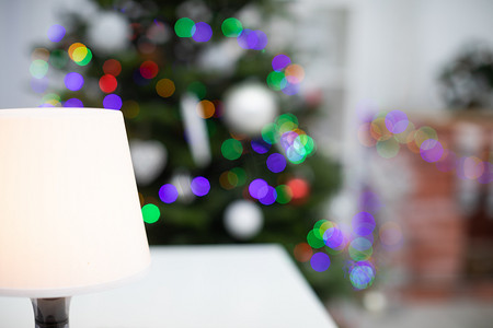 客厅灯光摄影照片_夜灯站在白色橱柜上，背景是一棵圣诞树，灯光带有散景效果。